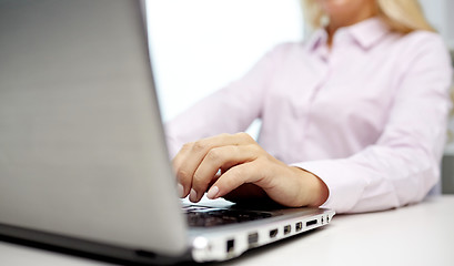 Image showing smiling businesswoman or student typing on laptop