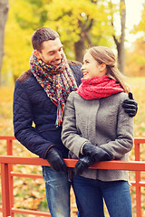 Image showing smiling couple hugging on bridge in autumn park