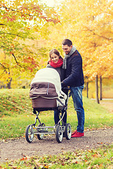 Image showing smiling couple with baby pram in autumn park