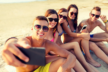 Image showing friends with smartphones on beach