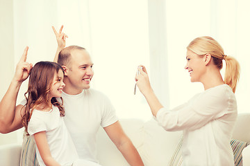 Image showing happy mother taking picture of father and daughter