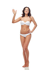 Image showing happy young woman in white swimsuit waving hand