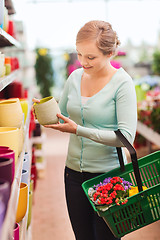 Image showing woman with shopping basket choosing flowerpot