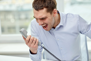 Image showing furious businessman calling on phone in office