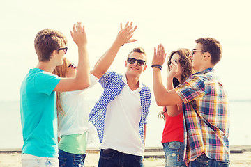 Image showing group of smiling friends making high five outdoors