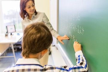 Image showing school boy with teacher writing on chalk board