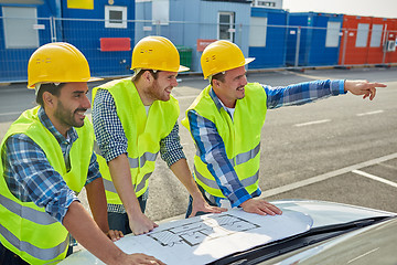 Image showing close up of builders with blueprint on car hood