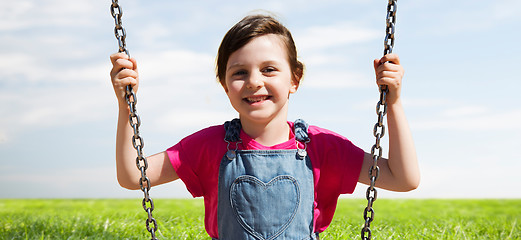 Image showing happy little girl swinging on swing outdoors