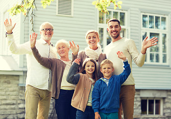 Image showing happy family waving hands in front of house