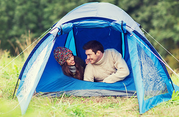 Image showing smiling couple of tourists looking out from tent