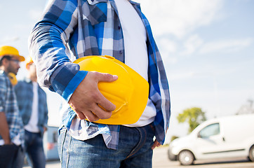 Image showing close up of builder holding hardhat at building