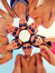 Image showing smiling friends in circle on summer beach