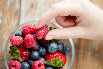 Image showing close up of woman hands with berries in glass bowl