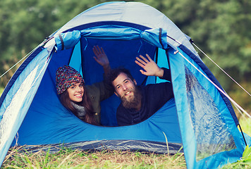 Image showing smiling couple of tourists looking out from tent