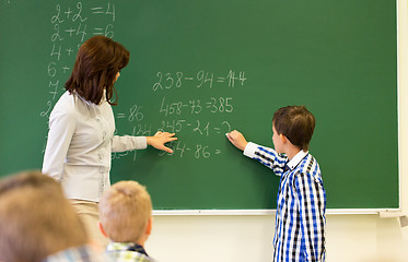 Image showing schoolboy with math teacher writing on chalk board