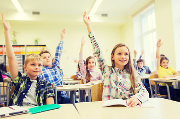 Image showing group of school kids raising hands in classroom