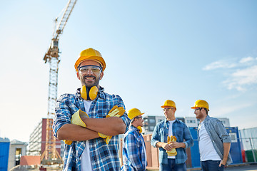 Image showing group of smiling builders in hardhats outdoors