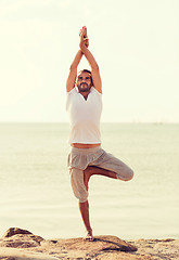 Image showing smiling man making yoga exercises outdoors