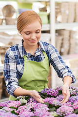 Image showing happy woman taking care of flowers in greenhouse