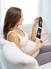 Image showing happy pregnant woman with ultrasound image at home