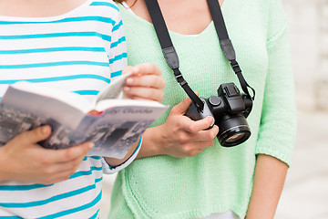 Image showing close up of women with city guide and camera