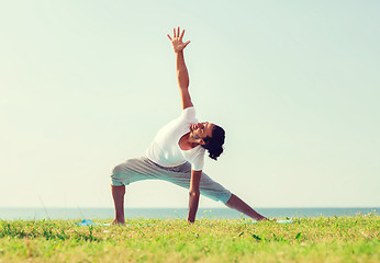 Image showing smiling man making yoga exercises outdoors