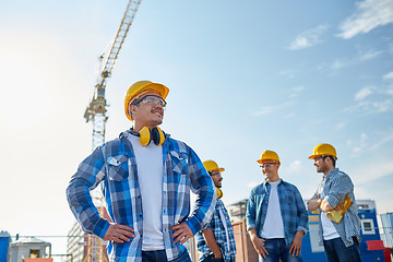 Image showing group of smiling builders in hardhats outdoors