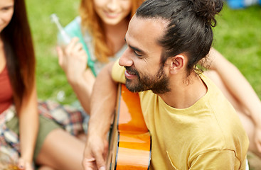 Image showing happy man with friends playing guitar at camping