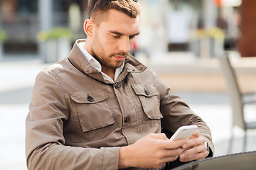 Image showing man with smartphone at city street cafe