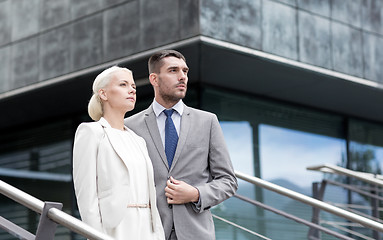 Image showing serious businessmen standing over office building