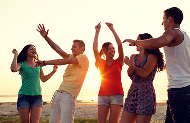 Image showing smiling friends dancing on summer beach