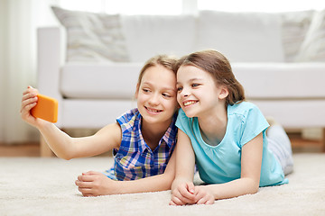 Image showing happy girls with smartphone taking selfie at home