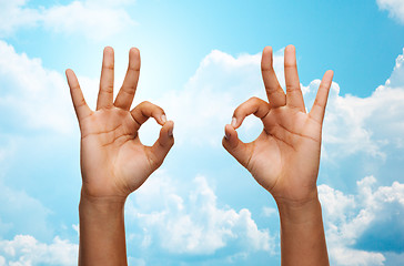 Image showing two african hands showing ok sign over blue sky