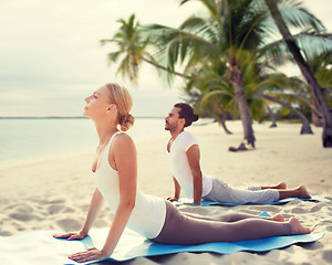 Image showing happy couple making yoga exercises on beach