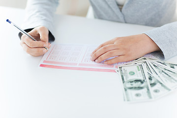 Image showing close up of hands with lottery ticket and money