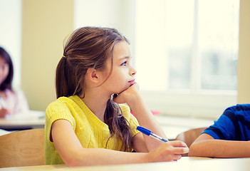 Image showing school girl with pen being bored in classroom