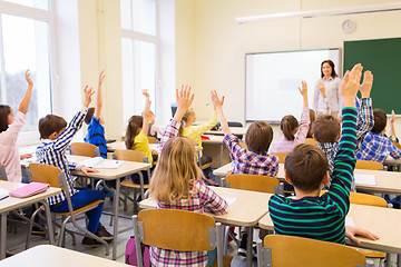 Image showing group of school kids raising hands in classroom