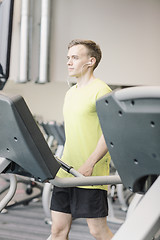 Image showing man with smartphone exercising on treadmill in gym