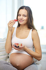Image showing happy pregnant woman eating fruits at home