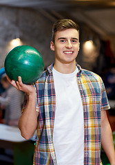 Image showing happy young man holding ball in bowling club