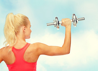 Image showing sporty woman with heavy steel dumbbell from back