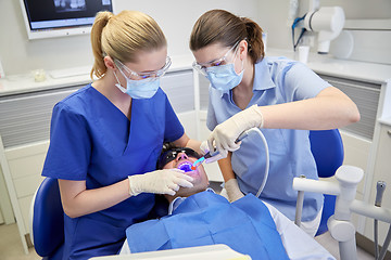 Image showing dentists treating male patient teeth at clinic