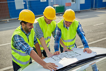 Image showing close up of builders with blueprint on car hood