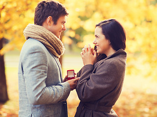 Image showing smiling couple with red gift box in autumn park