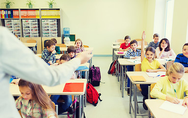 Image showing group of school kids raising hands in classroom