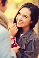 Image showing close up of smiling couple with gift box in park