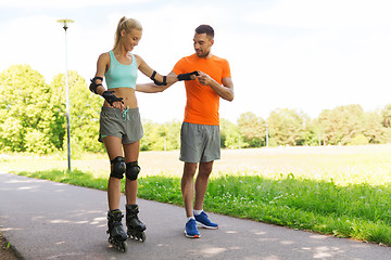 Image showing happy couple with roller skates riding outdoors