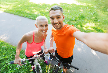 Image showing couple with bicycle taking selfie outdoors