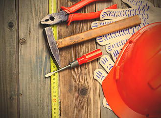 Image showing Vintage hammer, pliers, screwdriver, tape measure, a bright helm