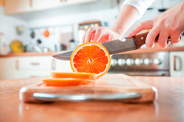 Image showing Woman\'s hands cutting orange